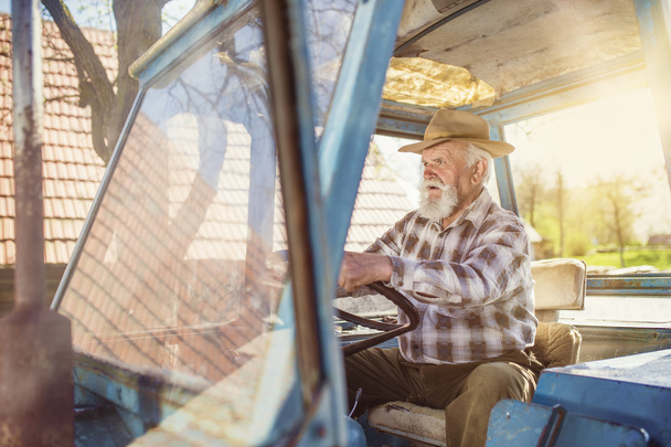 Senior farmer driving a tractor - Foto, afbeelding