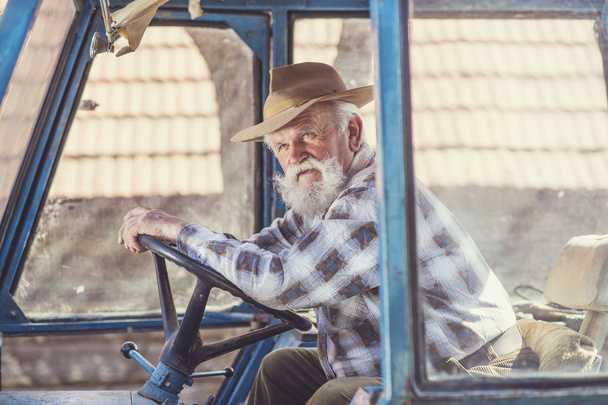 Senior farmer driving a tractor - Fotoğraf, Görsel