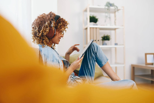 Evde Mutlu Kadın: Oturma odasında rahat bir koltukta otururken Tablet 'te Müzik ve Oyunlarla Rahatlamak - Fotoğraf, Görsel