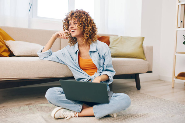 Mulher sorridente trabalhando no laptop na acolhedora sala de estar - Foto, Imagem