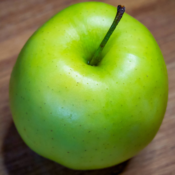 La superficie di legno sotto la mela aggiunge un tocco rustico e organico. - Foto, immagini