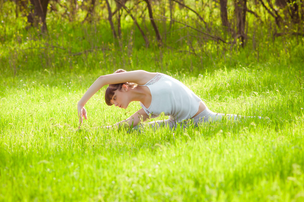 Young girl doing yoga on a green grass - Foto, Imagen