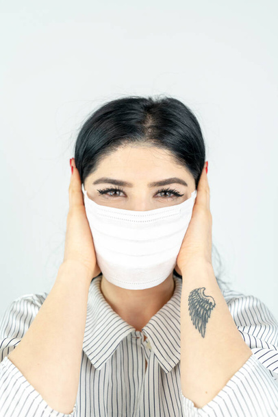 Mujer joven con máscara quirúrgica en la cara contra SARS-CoV-2. COVID-19 Pandemic Coronavirus Chica joven en habitación blanca con máscara facial - Foto, Imagen