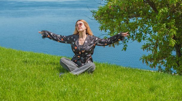 Concepto de curación y meditación de energía, mujer en una hierba que se enfría y descansa afuera - Foto, imagen