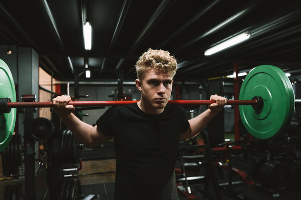 Cropped shot of a young male athlete working out with a barbell at functional training gym - Photo, Image