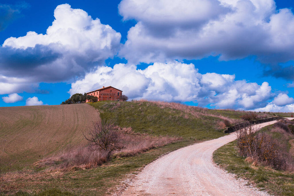 Zonnig Toscaans platteland: groene heuvels, blauwe lucht en vuile wegen - Foto, afbeelding