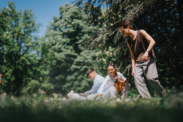 Це яскраве зображення захоплює молодих дорослих, які розмовляють у сонячному парку, оточеному високими деревами і травою. - Фото, зображення