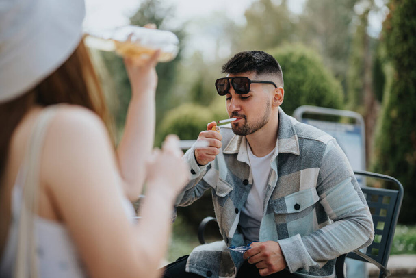 Eine Gruppe von Freunden trifft sich im Freien, genießt Snacks und Getränke in einem entspannten Rahmen und teilt Lachen und gute Zeiten an einem sonnigen Tag. - Foto, Bild