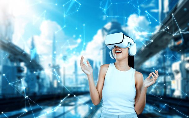 Weiblicher Stand trägt weißes VR-Headset und weißes ärmelloses connect metaverse, Zukunftstechnologie schafft Cyberspace-Community. Sie schaut sich um und gestikuliert und genießt es, in Meta Fantasie aufzubauen. Halluzination. - Foto, Bild