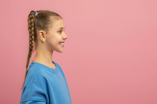 Une jeune fille avec une coiffure soigneusement tressée est présentée dans ce portrait. Sa tresse est bien en vue, ajoutant une touche d'élégance à son apparence, regardant l'espace de copie - Photo, image