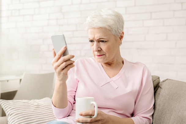 Myopie. Femme âgée tenant le téléphone près du visage, essayant de voir le message, espace libre
 - Photo, image