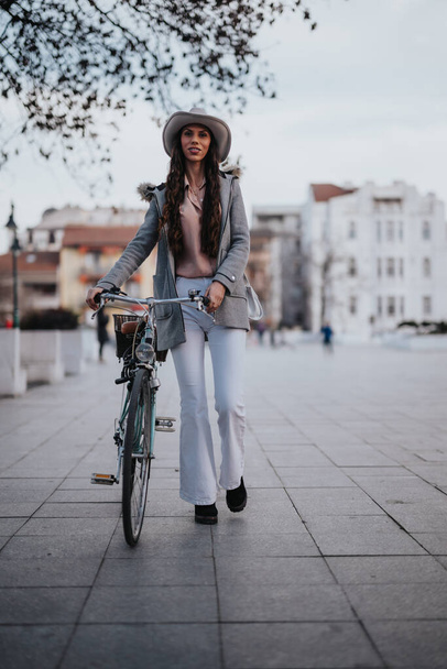 Kendine güveni tam bir iş kadını, şık giyinmiş, bisikletiyle sakin bir parktaki patikada.. - Fotoğraf, Görsel