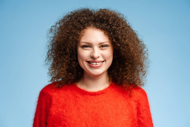 Portrét šťastné ženy středního věku se usmívá, na sobě červený útulný svetr izolovaný na modrém pozadí, detailní záběr. Zubní, koncept zdravotní péče - Fotografie, Obrázek