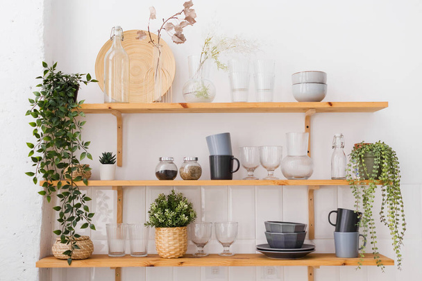 Półki drewniane z naczyniami i roślinami w kuchni na białym tle ścian - Zdjęcie, obraz