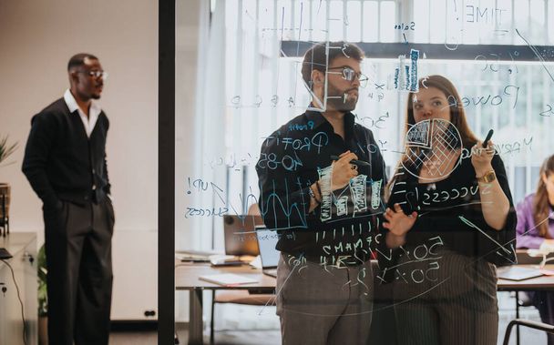Diverso gruppo di professionisti del business soluzioni di brainstorming e strategie su una parete di vetro ricoperta di grafica dinamica e appunti appiccicosi in un ufficio luminoso. - Foto, immagini