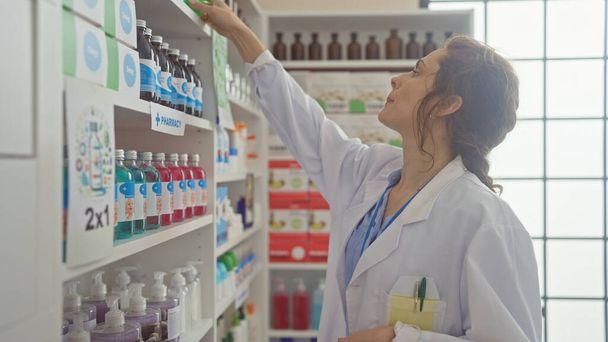 Mujer farmacéutica caucásica busca medicamentos en una farmacia soleada - Foto, Imagen