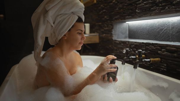 Entspannte Frau genießt luxuriöses Schaumbad in einem modernen Badezimmer zu Hause - Foto, Bild