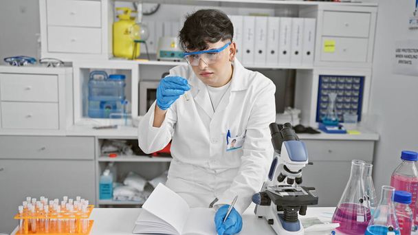 Un científico masculino enfocado analiza un tubo de ensayo en un laboratorio bien equipado, mostrando la investigación y la atención médica. - Foto, imagen