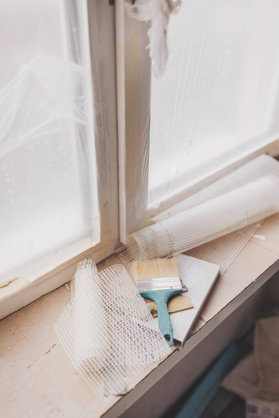 un pinceau sur un rebord de fenêtre prêt à fixer le mur. Appartement en construction dans le nouveau lotissement européen. - Photo, image