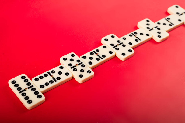 Kırmızı zemin üzerinde domino taşları. Beyaz Kemik Tahta Oyunu. - Fotoğraf, Görsel