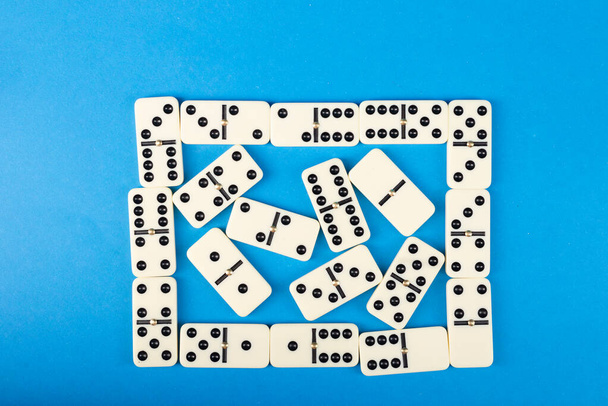 Ντομίνο σε μπλε φόντο. Επιτραπέζιο παιχνίδι λευκών οστών. - Φωτογραφία, εικόνα