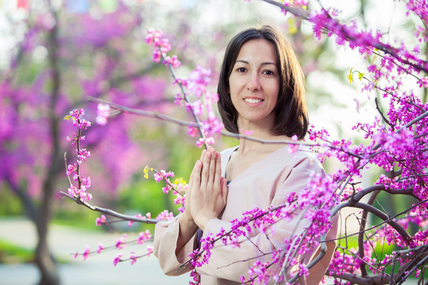 woman doing yoga on the background of a blooming garden, oriental cherry. - Photo, Image