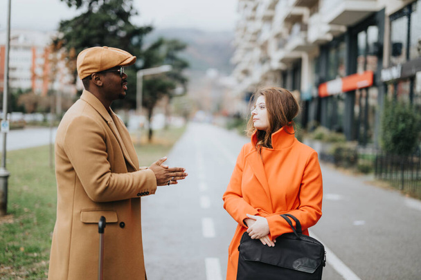 Ein stilvolles Businesspaar unterschiedlicher ethnischer Zugehörigkeiten führt auf der Straße ein Gespräch und stellt Work-Life-Balance und Partnerschaft dar. - Foto, Bild