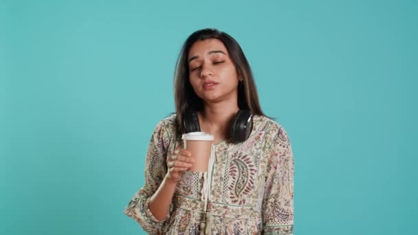 Sleepy woman yawning, sipping coffee to gain energy and get rid of headache. Exhausted person feeling fatigued after sleepless night, drinking caffeinated beverage, studio backdrop, camera A - Footage, Video
