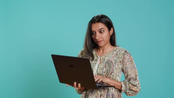 Indická žena skládající e-mail, psaní na notebooku, frustrovaná chybnou klávesnicí. Osoba odesílající poštu online, snaží se používat vadný notebook, studio pozadí, kamera A - Záběry, video