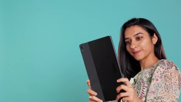 Indyjska narcystyczna kobieta używająca tabletki do robienia selfie ze wszystkich stron. Próżny użytkownik mediów społecznościowych robi zdjęcia za pomocą aparatu fotograficznego selfie urządzenia cyfrowego, uśmiechając się szczęśliwie, tło studio, aparat B - Materiał filmowy, wideo