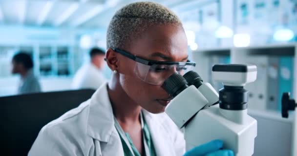 Наука, дослідження та чорна жінка на мікроскопі перевірки результатів фармацевтичного тесту в лабораторії. Окуляри, безпека та вчений вивчають зразок з медичними інноваціями для розвитку вакцин. - Кадри, відео
