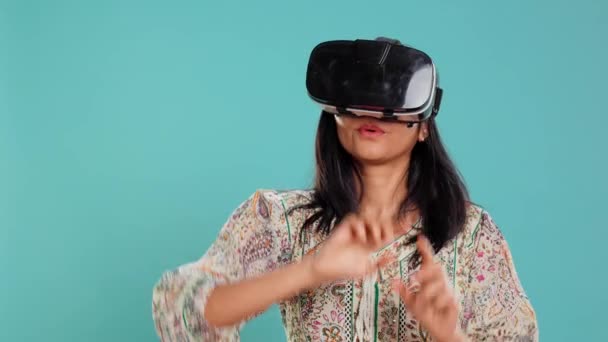 Індійська жінка в гарнітурі віртуальної реальності, робить жести. Технологічний ентузіазм з використанням високотехнологічного футуристичного сучасного VR-гаджета, ізольованого над студійним фоном, камери B - Кадри, відео
