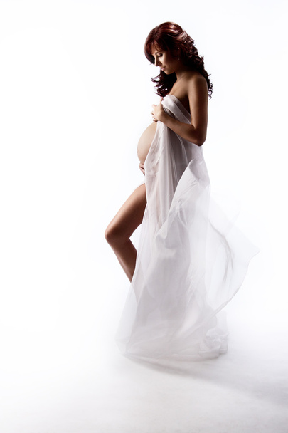 Pregnant woman in white waving flying dress. Looking down at be - Фото, изображение