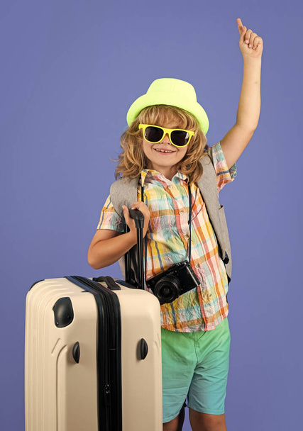 Kinder reisen. Glücklicher kleiner Junge mit Reisemütze und Koffern auf Studiohintergrund. Koffer mit Reisezubehör. Lebensstil und Reiseträume - Foto, Bild