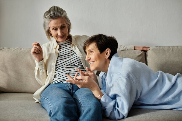 Zwei ältere Frauen sitzen auf einer bequemen Couch und vertiefen sich in ein tiefes Gespräch. - Foto, Bild