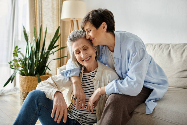 Zwei ältere Frauen umarmen sich herzlich auf einer Couch. - Foto, Bild