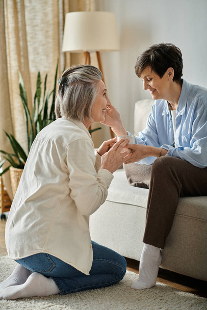 Mature lesbian couple engaged in heartfelt conversation on a cozy couch. - Photo, Image