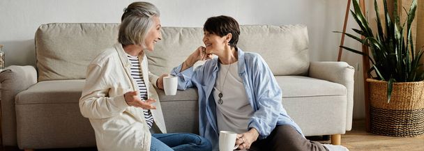 Two mature women sitting on floor, engaged in conversation. - Photo, Image