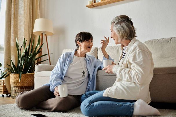 Two elderly women sitting on floor, engaged in conversation. - Photo, Image