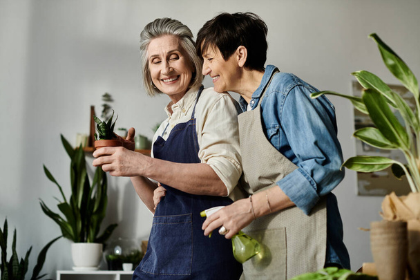 Two women in aprons care for a potted plant together. - Photo, Image
