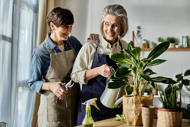 Mature lesbian couple in aprons nurturing a plant together. - Photo, Image