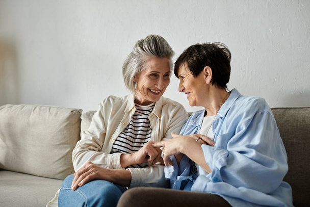 Δύο ηλικιωμένες γυναίκες απολαμβάνουν μια εγκάρδια συζήτηση σε έναν καναπέ. - Φωτογραφία, εικόνα
