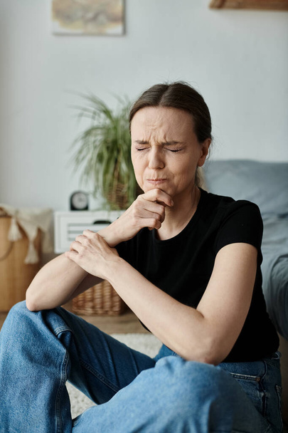 Middle-aged woman sitting on floor, hand on chin, deep in thought. - Photo, image