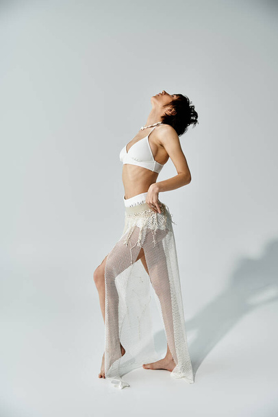 Young woman exudes elegance in a white bikini on a white backdrop. - Zdjęcie, obraz
