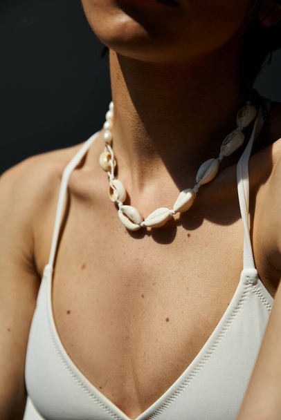 A young woman gracefully wearing a seashell necklace. - Valokuva, kuva