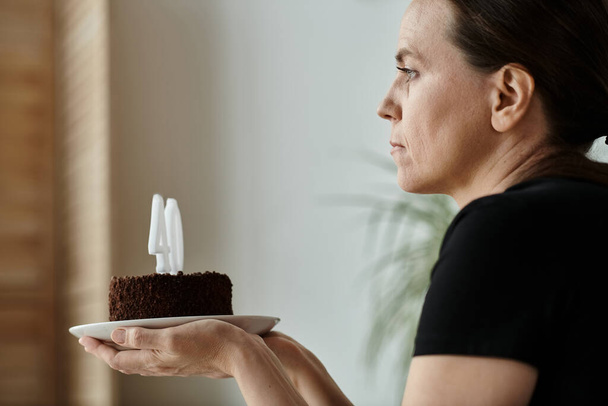 Woman holds cake with number, celebrating milestone. - Foto, afbeelding