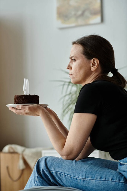 Woman sitting on couch, holding birthday cake. - Zdjęcie, obraz