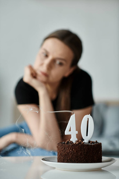 Middle-aged woman gazes at a birthday cake, pondering the significance of turning 40. - Foto, Imagem