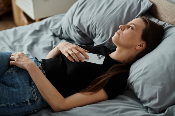 A woman in bed with her phone, engaging deeply with digital connection. - Foto, Imagen