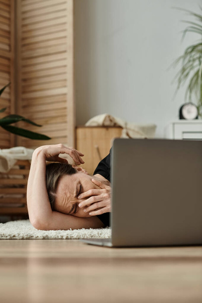 Middle-aged woman lying on floor with laptop, seeking online therapy. - Valokuva, kuva